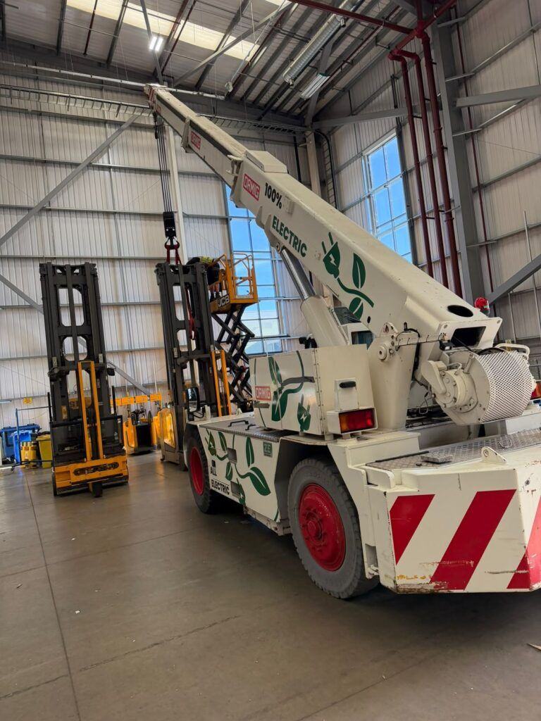 Electric pick-and-carry crane positioning a VNA truck mast inside a warehouse